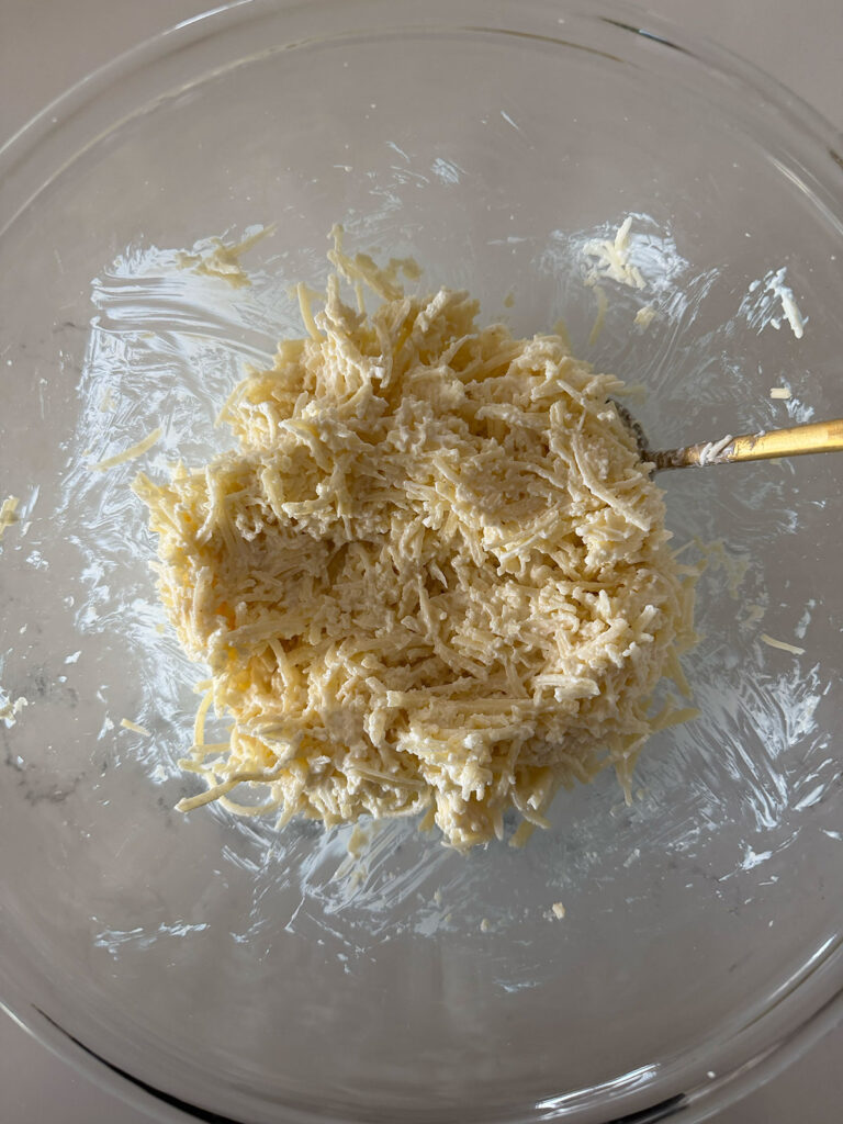 cheese mixture in clear bowl with gold utensil