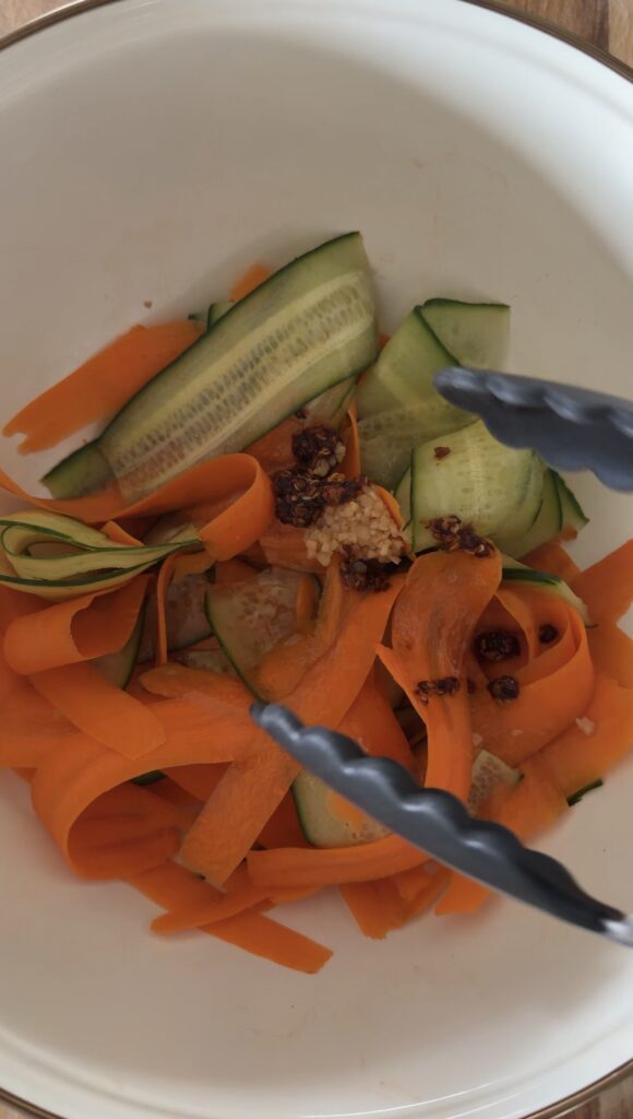 dressing ingredients in bowl with carrots and cucumbers