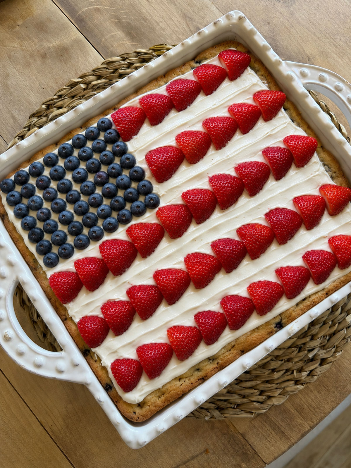 A flag cake in a white baking dish on a trivet.