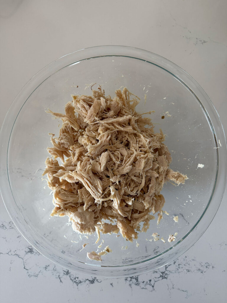 A glass bowl with shredded chicken.