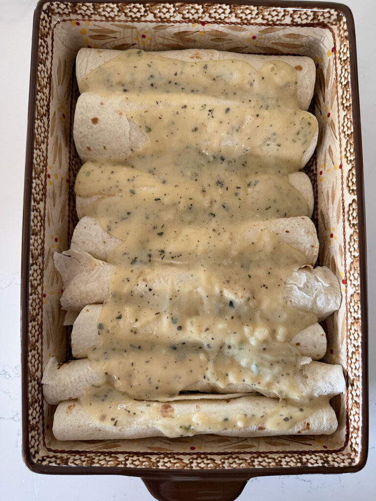 A baking dish with whit chicken enchiladas assembled before baking.
