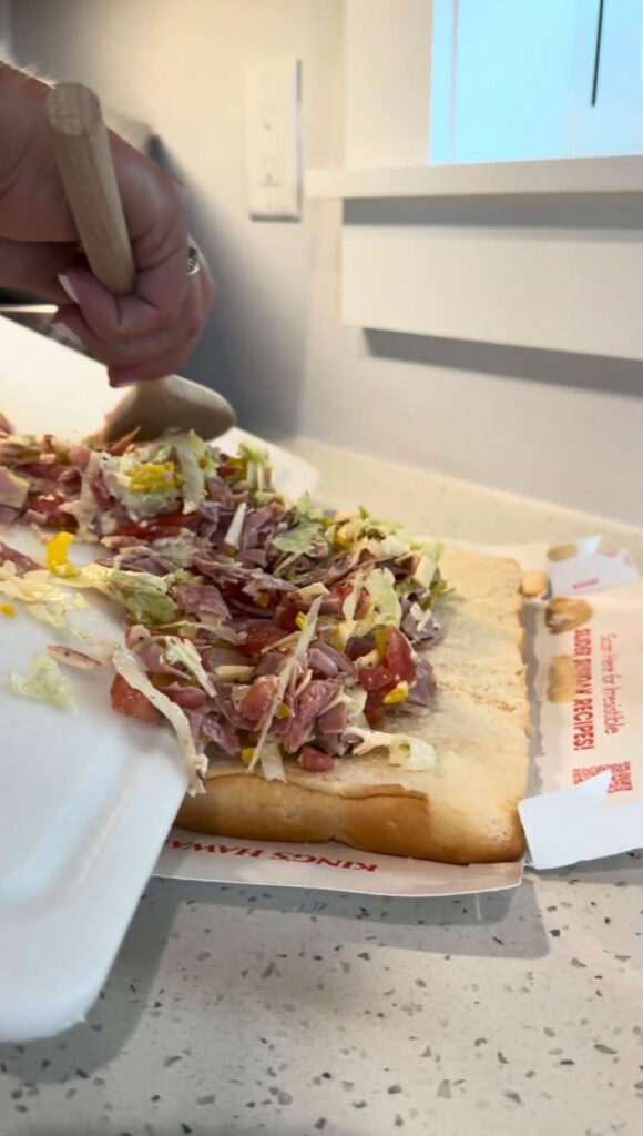 Putting the chopped Italian slider filling onto slider rolls.