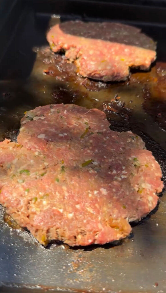 Smashed pickle burger patties on a griddle.