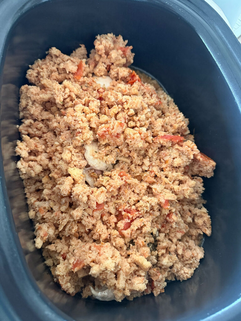 Bruschetta chicken ingredients plus stuffing mix on top in the slow cooker.