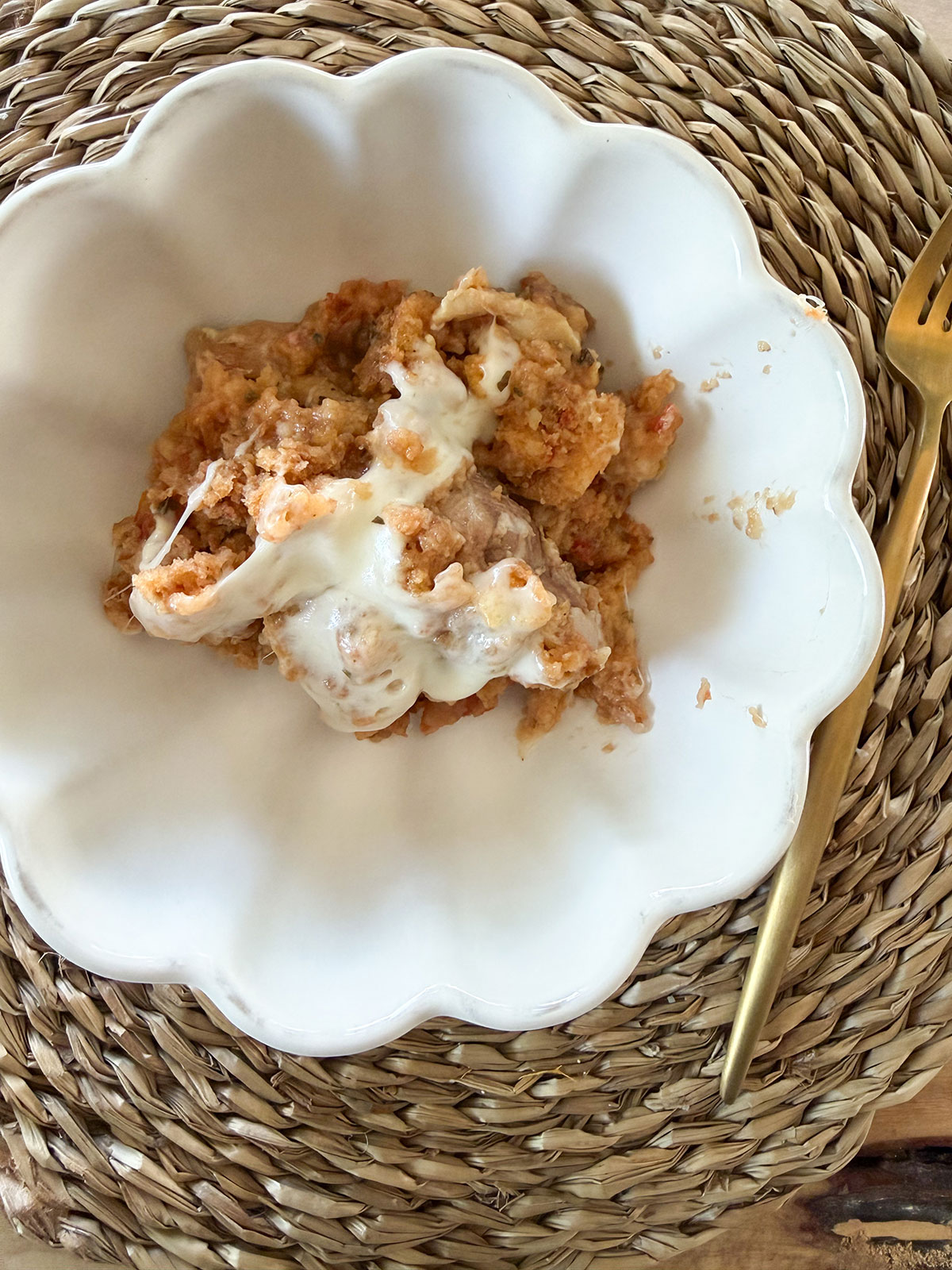 A white bowl with bruschetta chicken with a gold fork on the side.