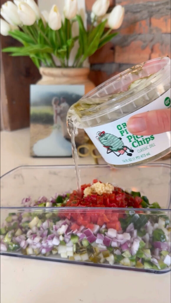 A hand adding pickle bring to pickle salsa.