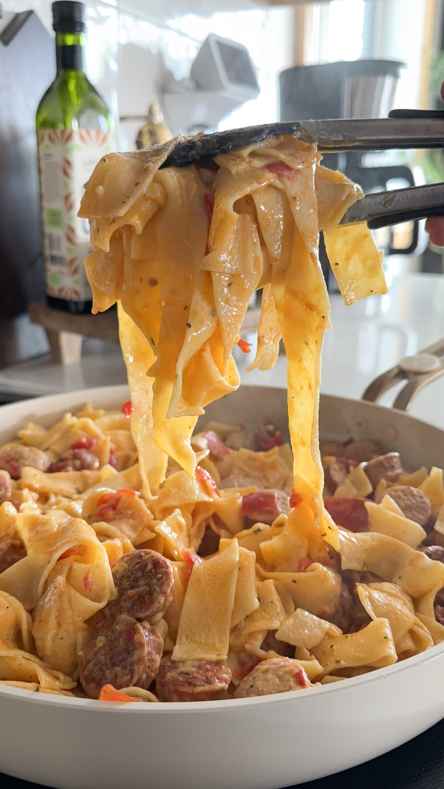noodles hanging off of tongs.