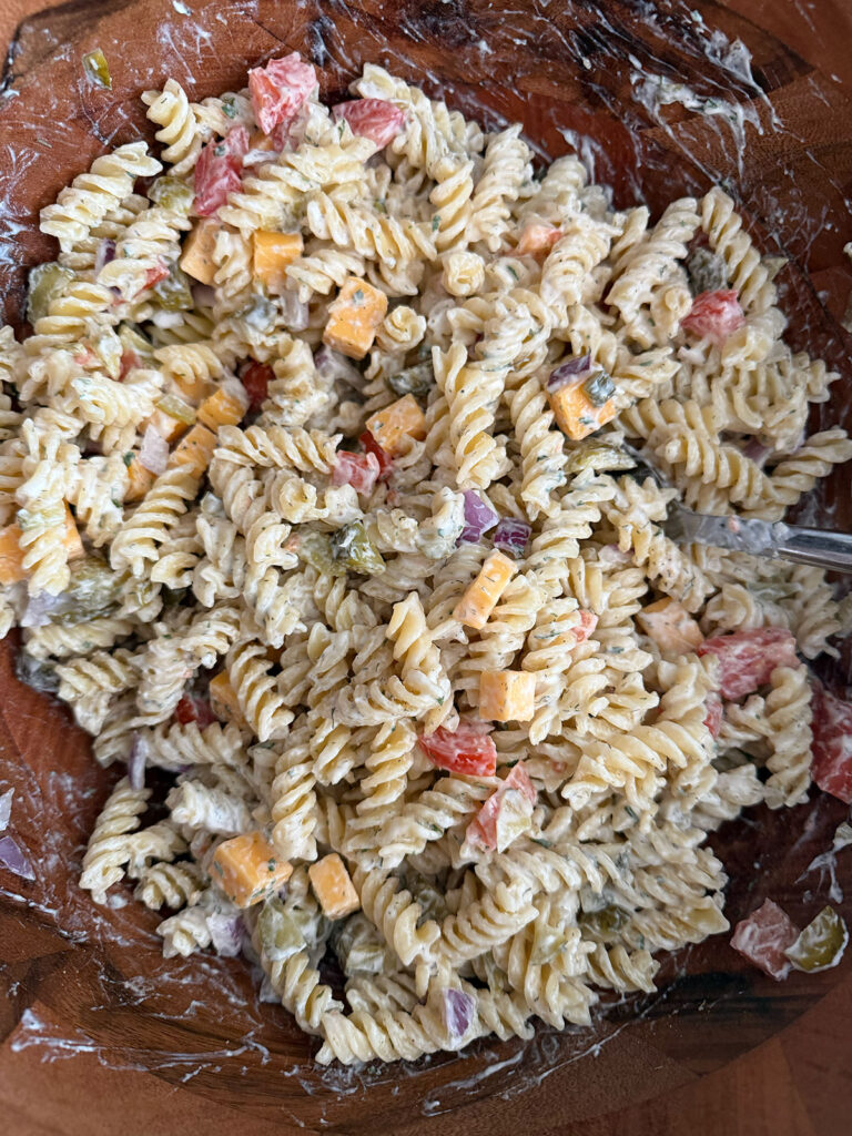 A wooden bowl with mixed dill pickle pasta salad.