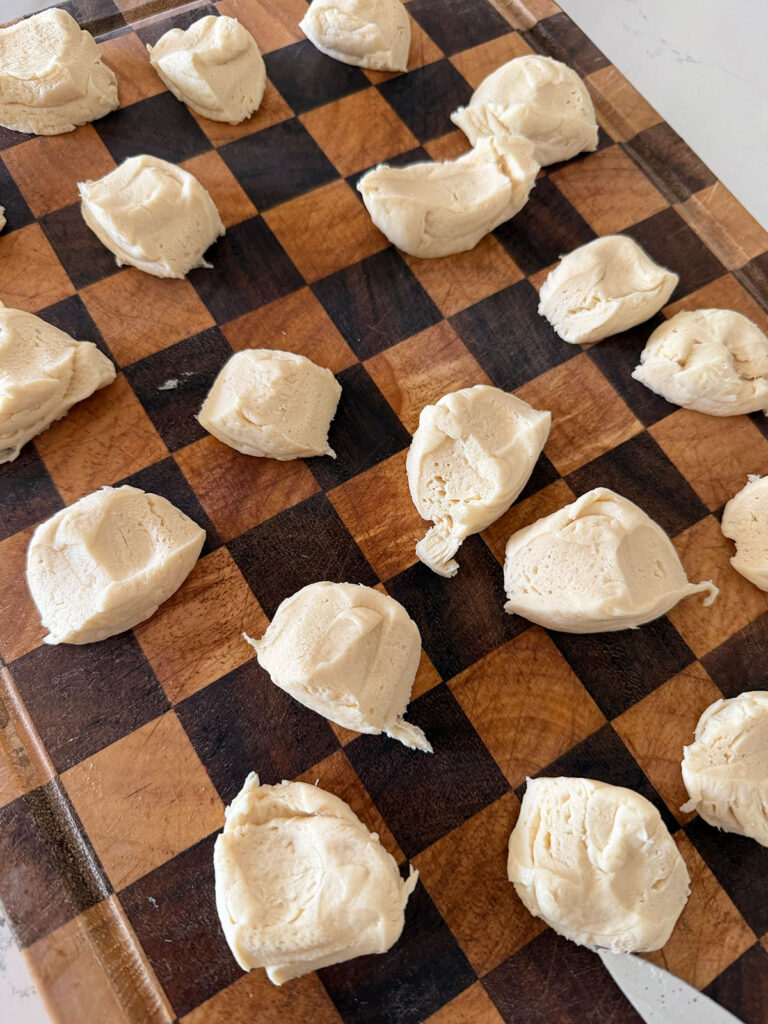 A checkered cutting board with cut biscuit pieces.