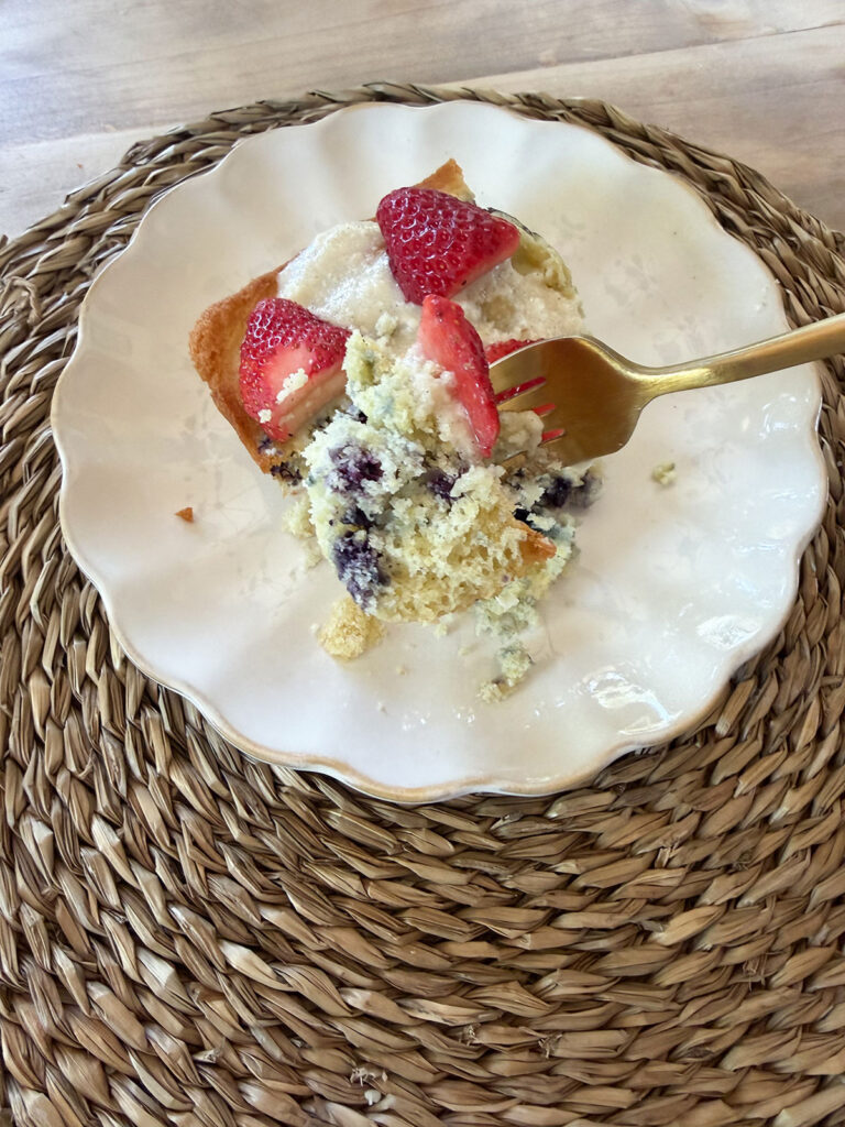A fork taking a bite of a piece of flag cake on a white plate.