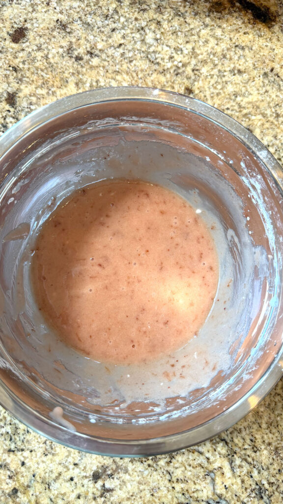 A metal bowl with strawberry glaze mixed.