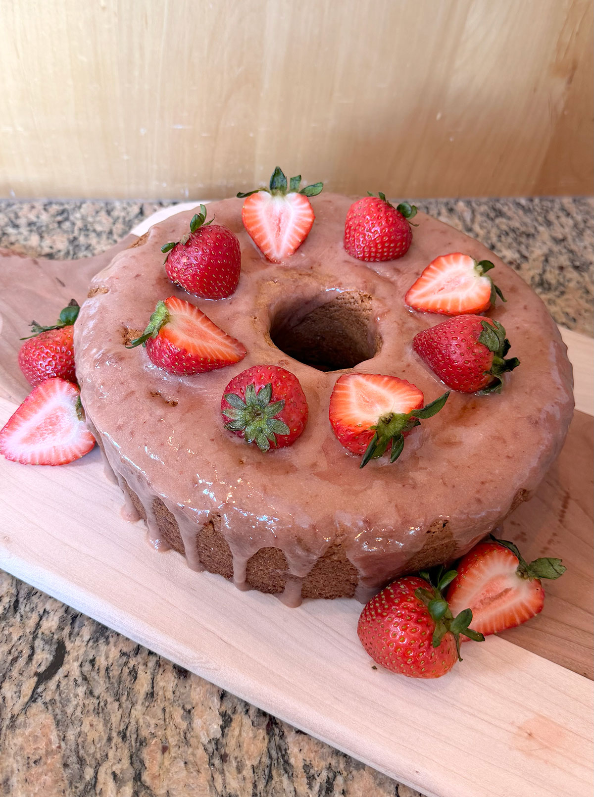 Strawberry bundt cake on a wooden cutting board.