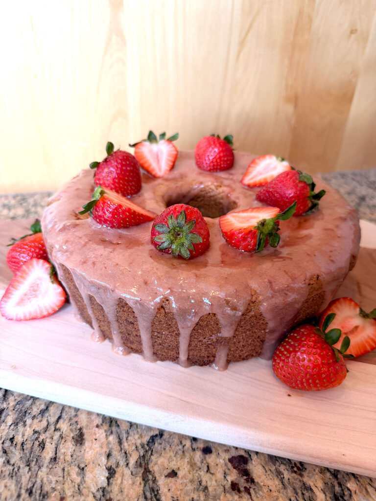 Strawberry bundt cake on a wooden cutting board.