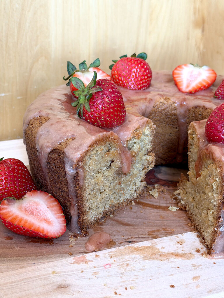 Cut open strawberry bundt cake on a wooden cutting board.