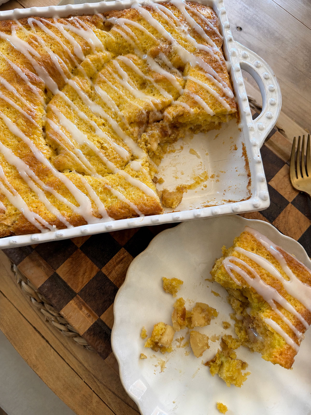 baked apple pie cake in baking dish with white side plate next to it with slice of apple pie cake