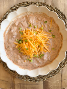 dip in a bowl topped with cheese and green onions