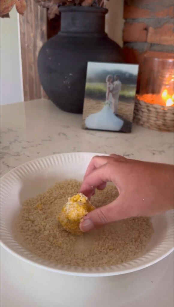 hand rolling dredged fried pickle cheese ball in panko breadcrumbs