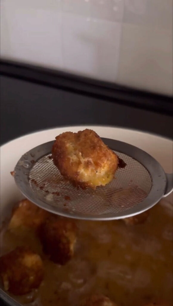 fried pickle cheese ball on spider/sieve, coming out of hot oil