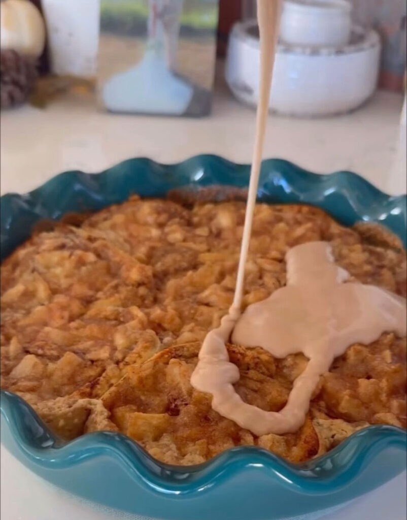 pie plate of cinnamon rolls with icing drizzling over top