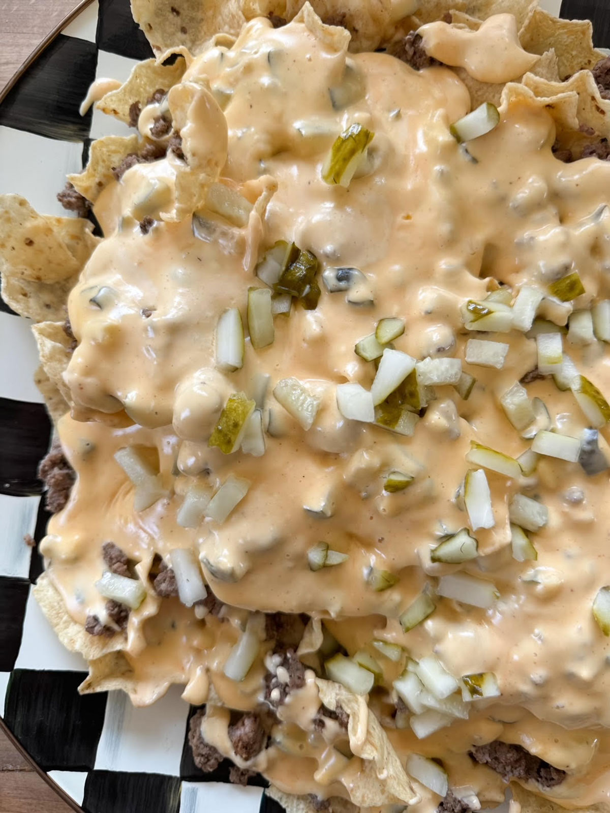 overhead shot of nachos on plate with meat, toppings and cheese sauce