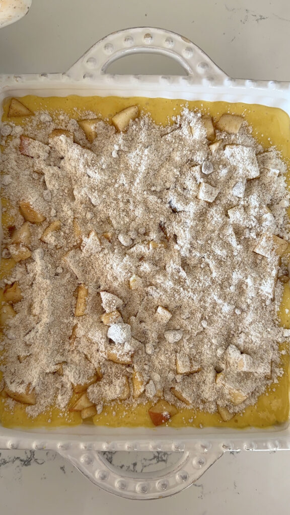 apple pie cake batter with diced apples and crumb topping ready to be baked