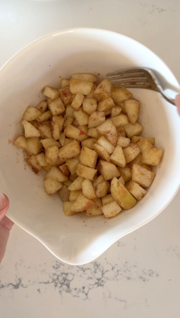diced apples with fork in white mixing bowl