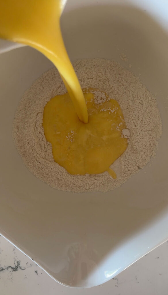 egg mixture added to flour in white bowl