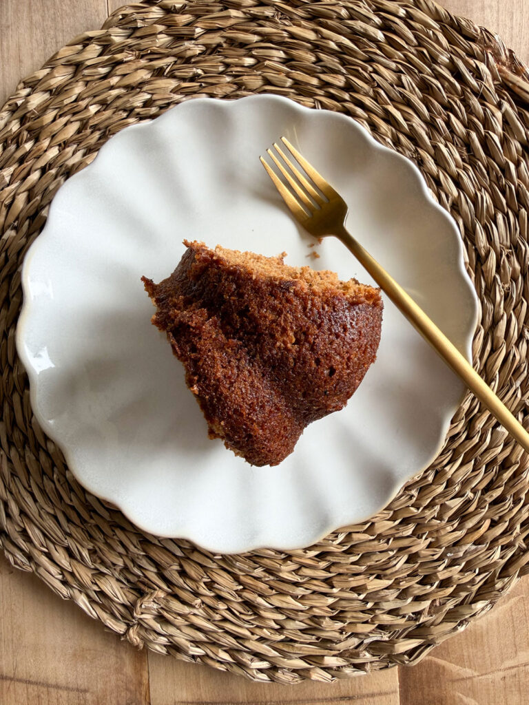 overhead shot of slice of applesauce cake on white plate with gold fork