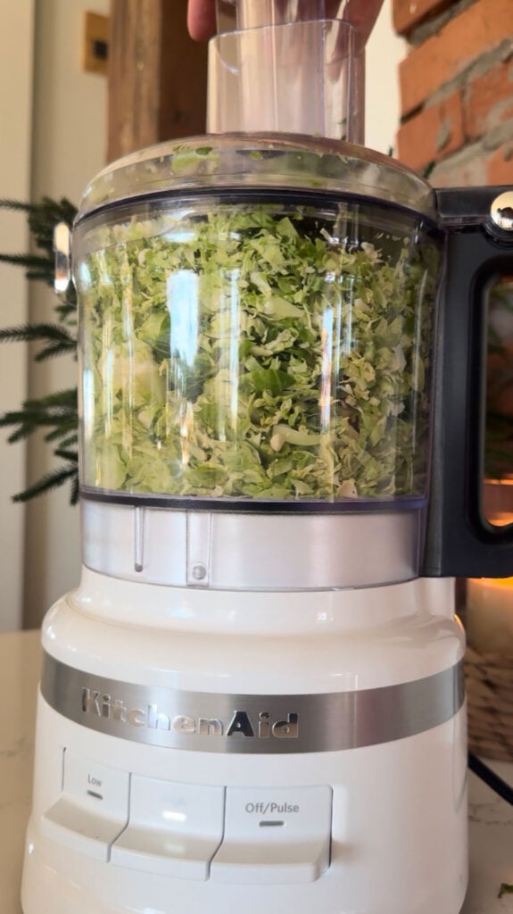mini food processor with shaved brussels sprouts in it