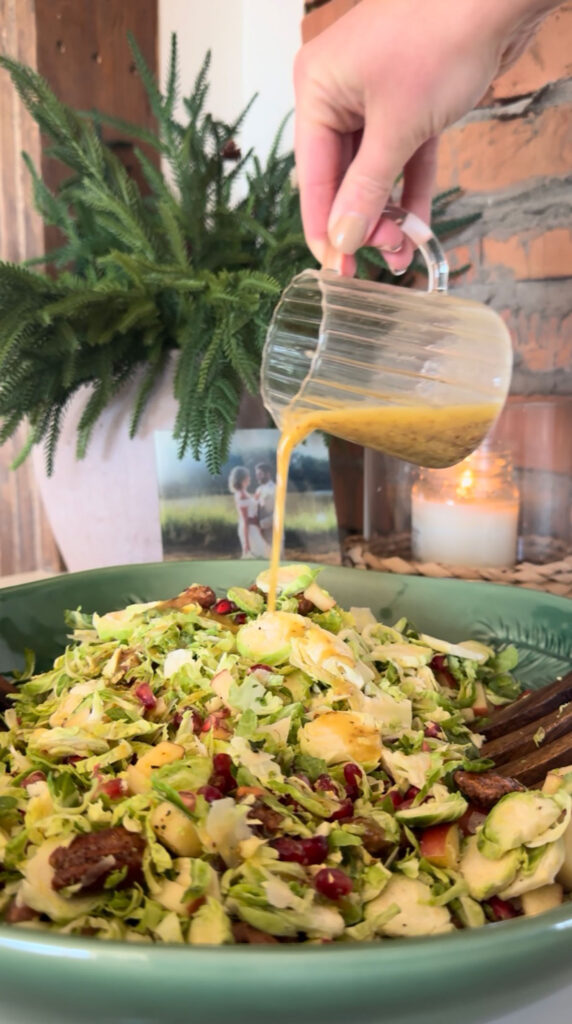 hand pouring dressing over brussels sprouts salad