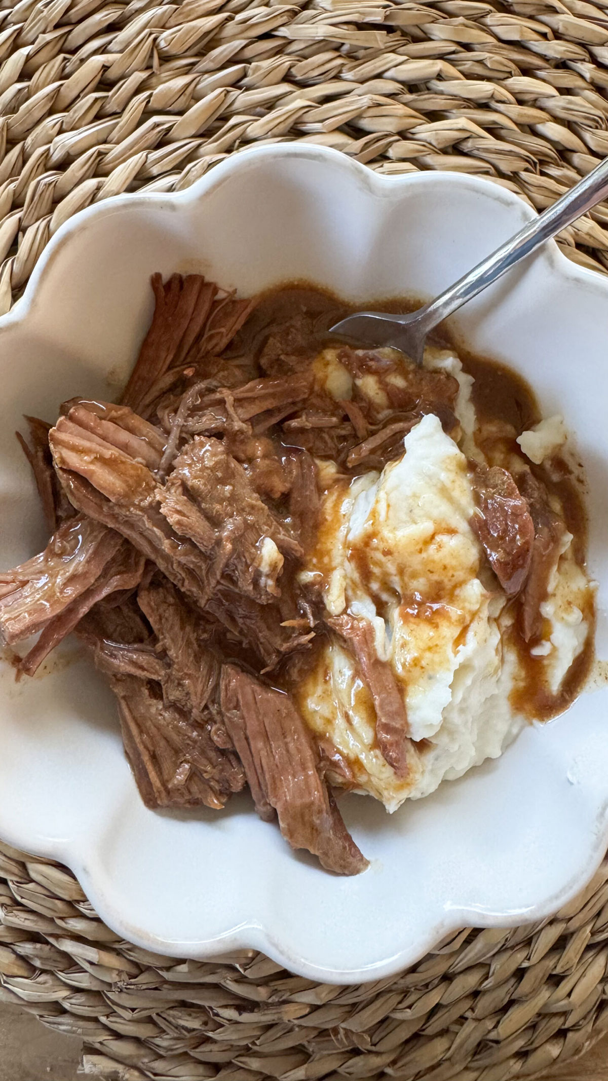 crockpot pot roast in white bowl with mashed potatoes and fork