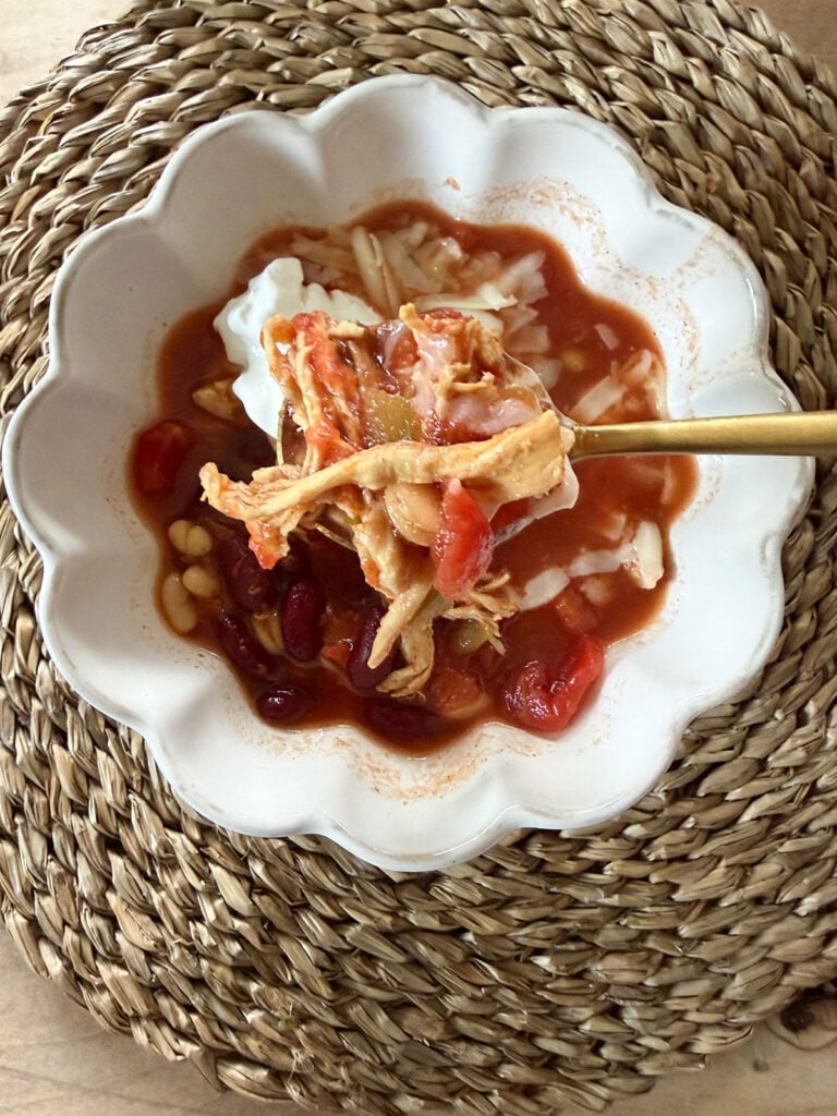 turkey chili in white bowl with gold spoon