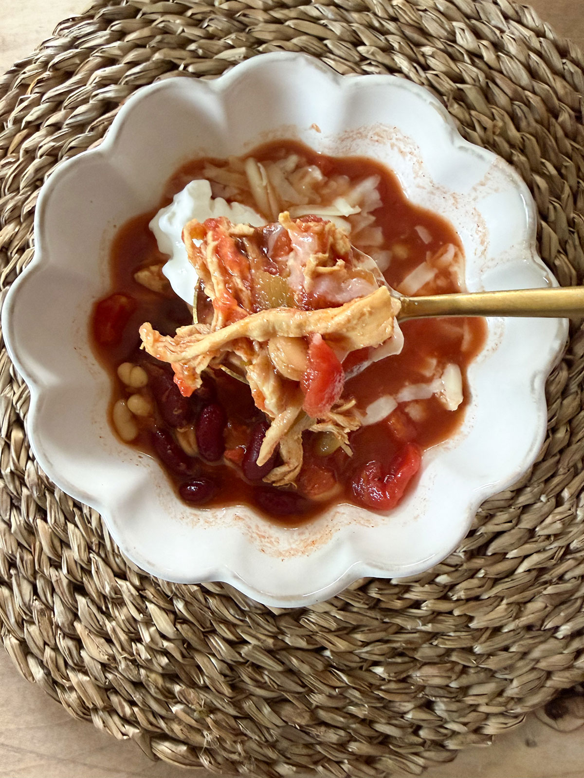 turkey chili in white bowl with gold spoon