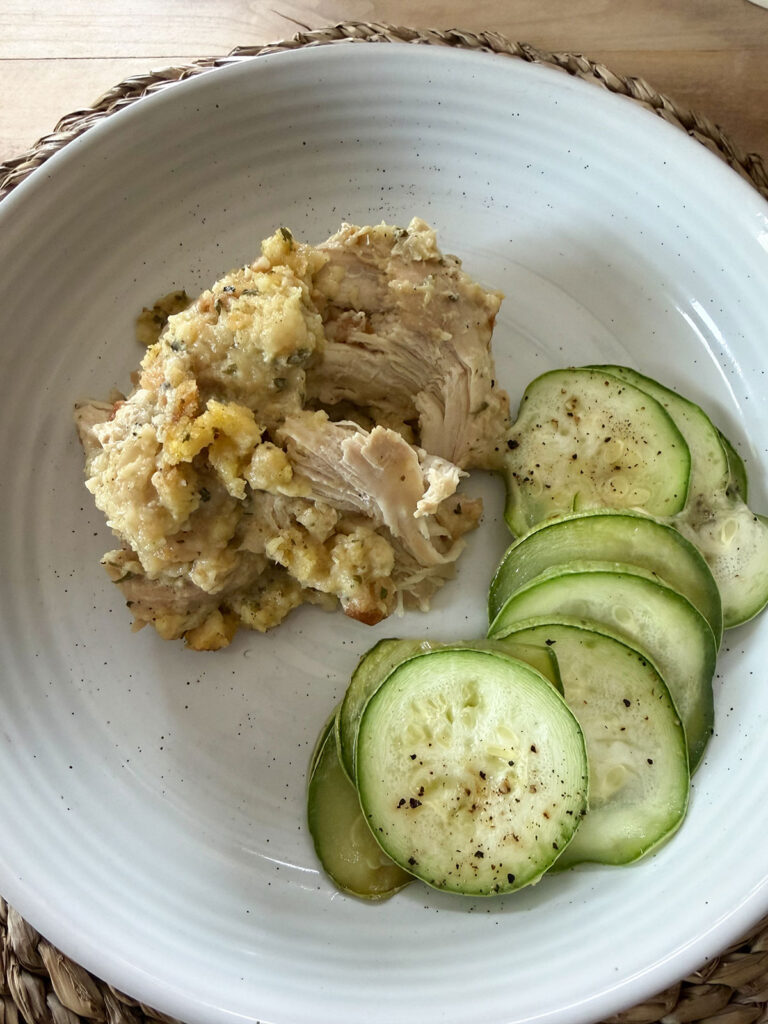 crockpot chicken and stuffing on white plate next to sliced zucchini