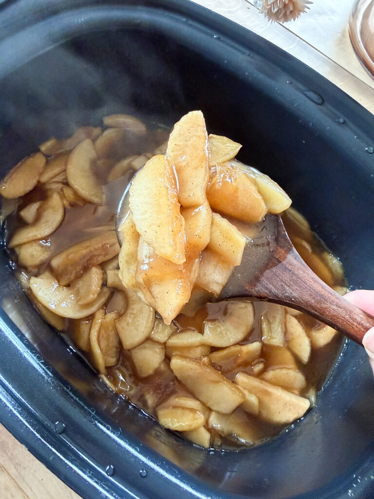 wooden spoonful of cinnamon apples in slow cooker
