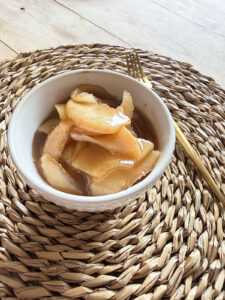 slow cooker cinnamon apples in white bowl with gold fork on side