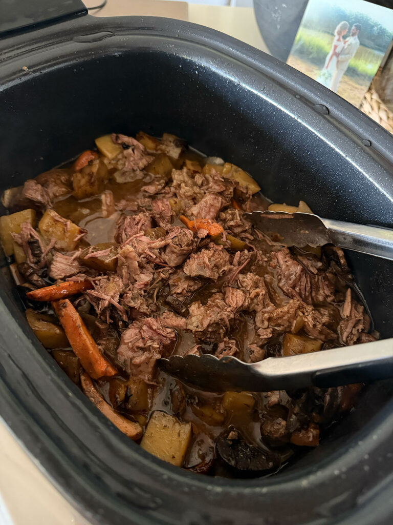 crockpot pot roast in slow cooker with tongs