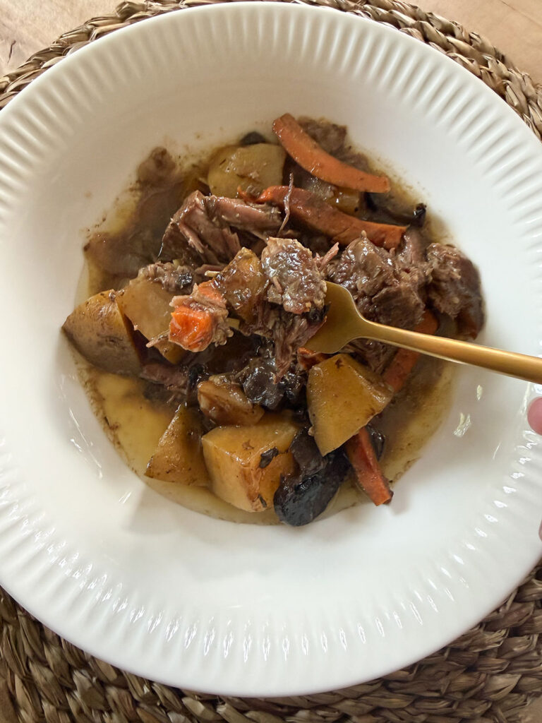 crockpot pot roast in white bowl with gold fork