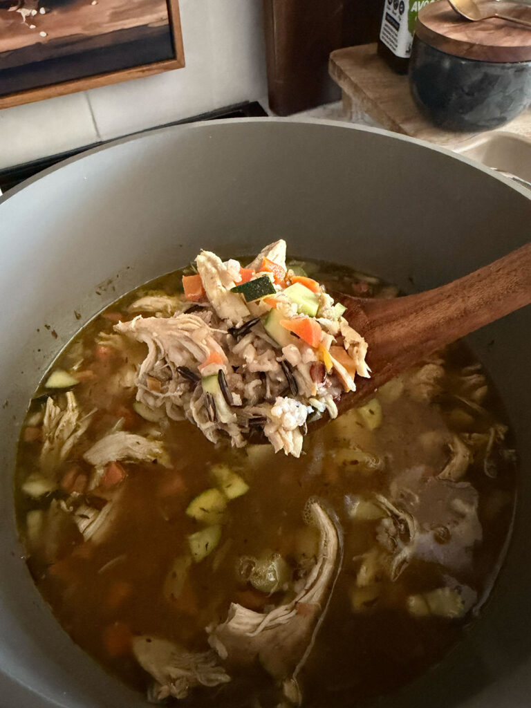 wooden spoonful of turkey and rice soup in pot