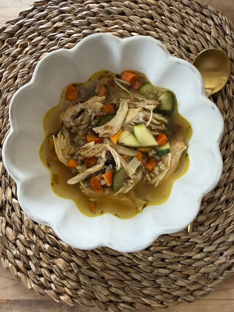turkey and rice soup in white bowl with gold spoon next to bowl