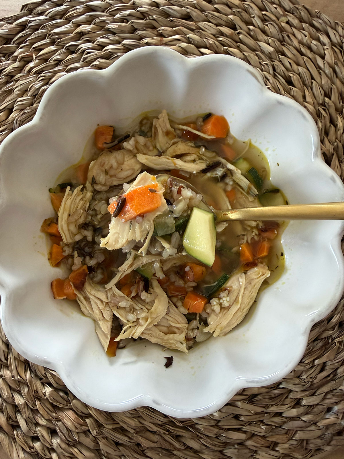 turkey and rice soup in white bowl with gold spoon