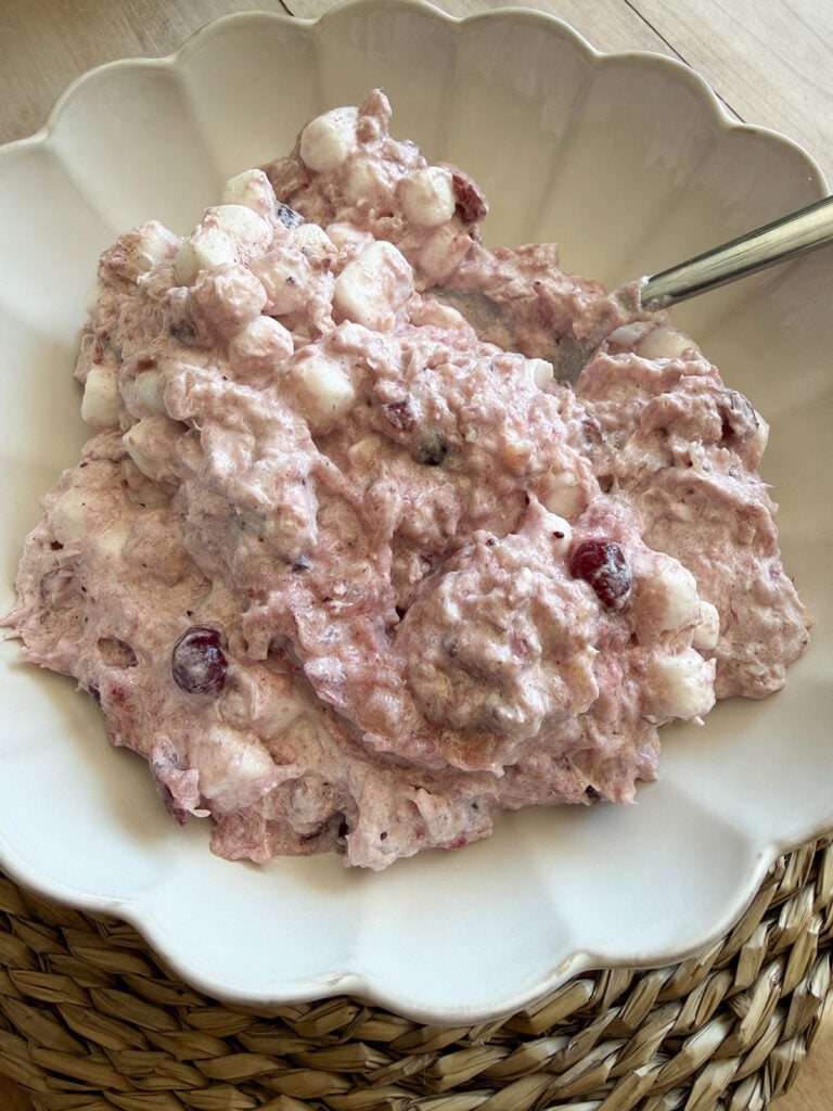 Overhead view of cranberry fluff in white scalloped bowl with spoon