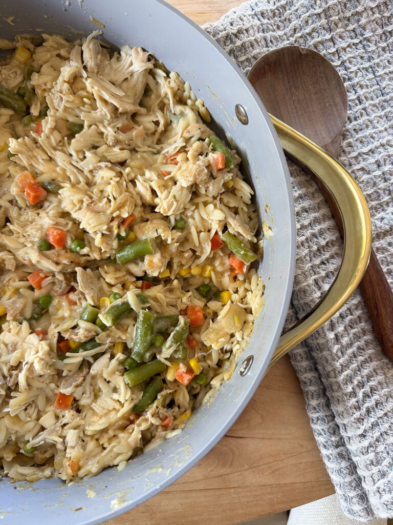 chicken pot pie orzo in pot with wooden spoon next to it