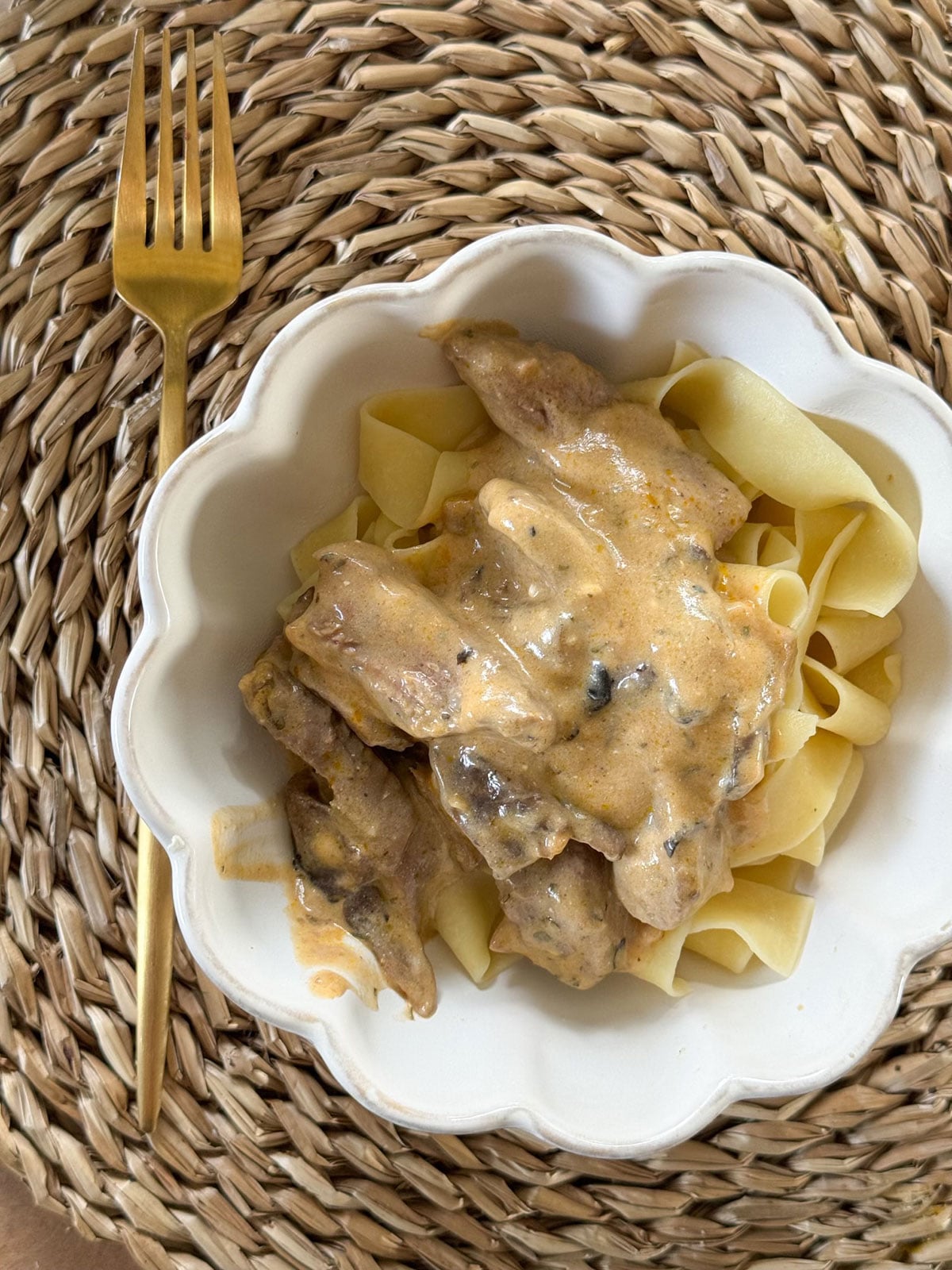stroganoff in white bowl on placemat with gold fork