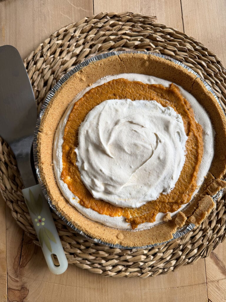 whole no bake pumpkin pie on placemat with serving spatula next to it
