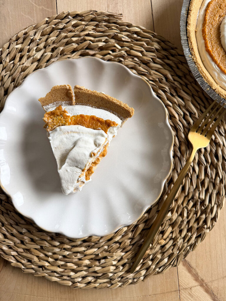 slice of no bake pumpkin pie on white plate on placemat next to gold fork