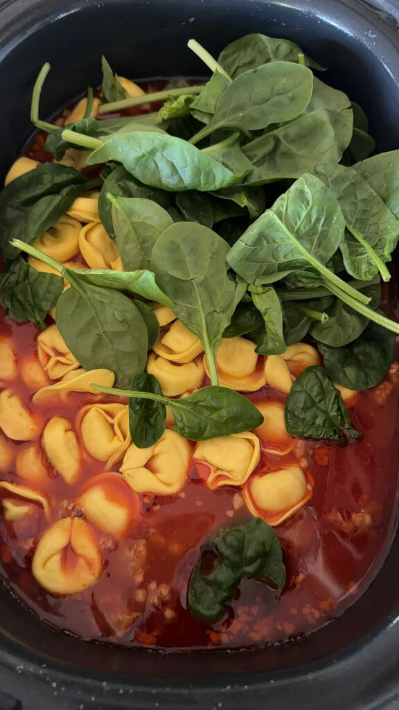 spinach being added to slow cooker and soup