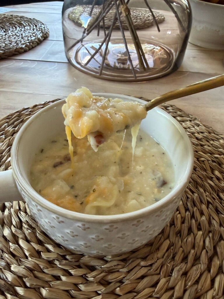 loaded potato soup in white crock with gold spoon on placemant