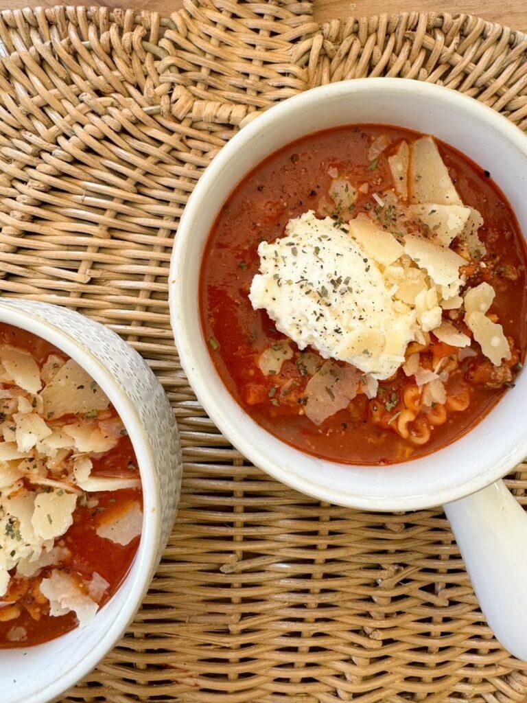 A white bowl of lasagna soup on a wicker placemat. 