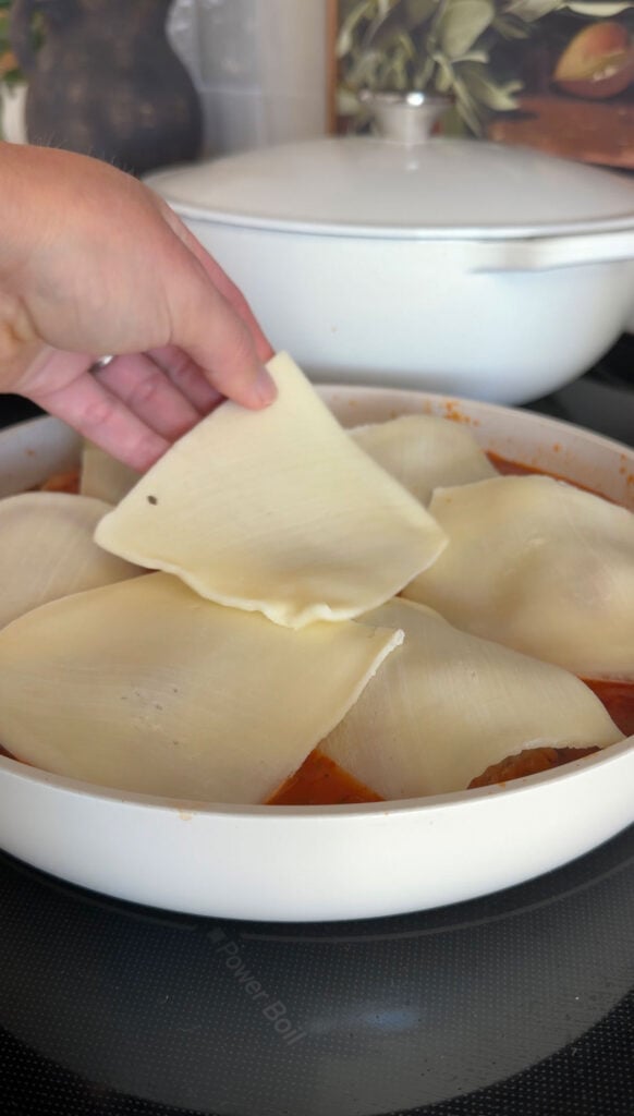 A hand placing cheese over chicken parm meatballs.